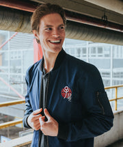 Dark blue bomber jacket influenced by the Chinese Zodiac Rat with a zipper on the left sleeve and the rat birth year on the right sleeve. Has the rat characteristic on the left chest with red and black pattern inside the jacket. Back of the Jacket is an embroidery of the Rat. Inside pocket on the left side.