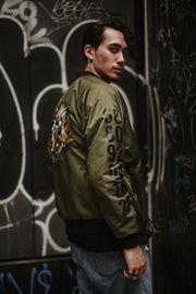Olive nylon bomber jacket, influenced by the Chinese Zodiac Monkey with zipper on the left sleeve and the monkey birth year on the right sleeve.  Has the monkey characteristic on the left chest with orange and black design inside the jacket. Back of the Jacket is an embroidery of the Monkey with inside pocket on the left side.